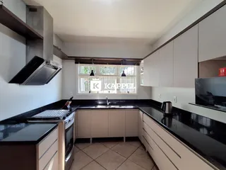 Cozinha moderna com armários brancos e bancadas escuras.