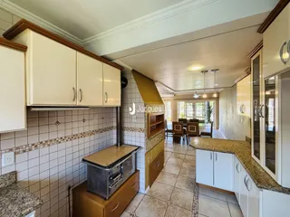 Vista da cozinha com armários brancos e revestimento de azulejos na Lajeado.