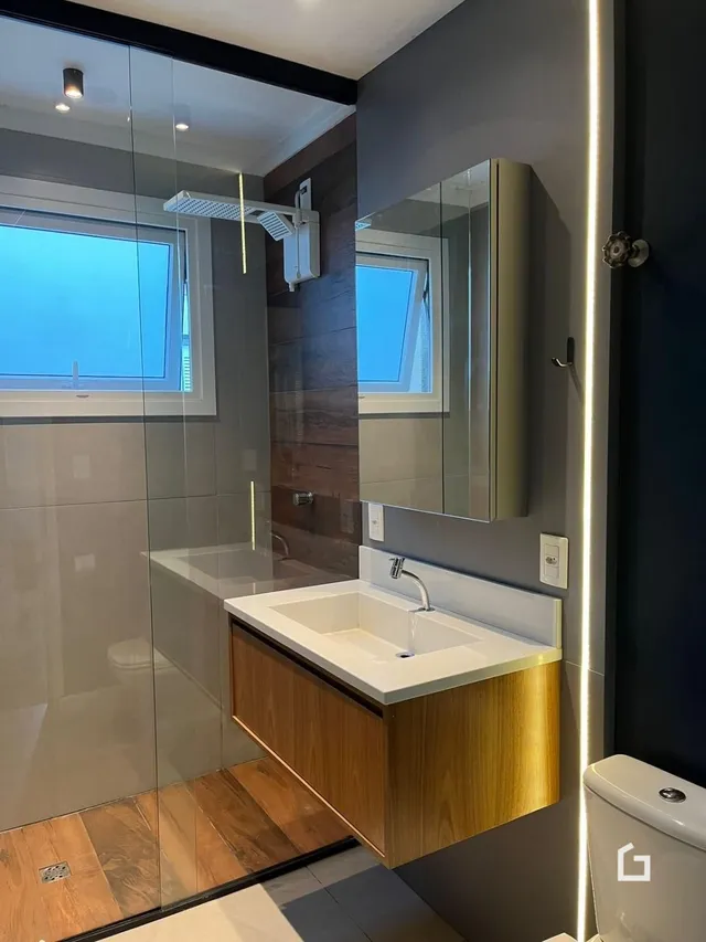 Foto de um banheiro moderno com box de vidro e bancada de madeira.