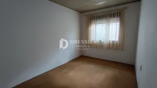 Ambiente interno de uma sala com piso de madeira e janela iluminada.