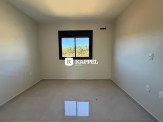 Vista interna de um cômodo com piso de cerâmica e janela para a paisagem externa.