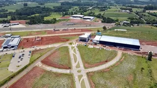 Vista aérea de uma propriedade com grandes áreas de campo e estruturas industriais.