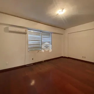 Sala de estar com piso de madeira e janela com persianas.