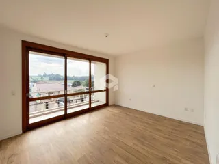 Sala de estar com piso de madeira e porta de vidro com vista para o exterior.