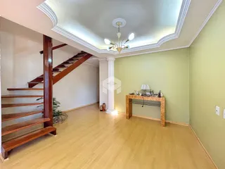 Interior de uma sala com piso de madeira e escadaria de madeira.