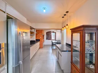Cozinha moderna com armários brancos e piso claro.