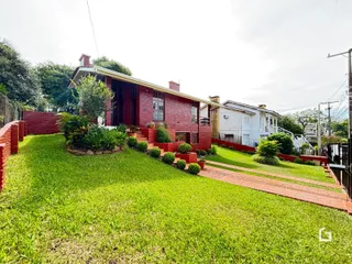 Fachada de uma casa de tijolos vermelhos com jardim gramado em Lajeado.