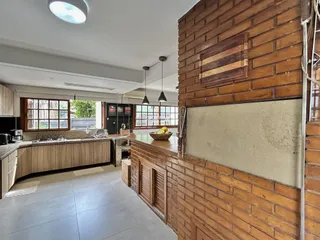 Vista de uma cozinha aberta com parede de tijolo aparente.