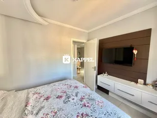 Quarto com cama e televisão em uma parede de madeira.