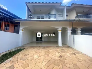Fachada de uma casa branca com telhado de telhas e área de entrada coberta.