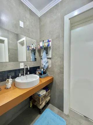 Foto de um banheiro com bancada de madeira e azulejos azuis.