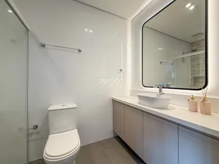 Interior de um banheiro moderno com azulejos brancos e bancada clara.