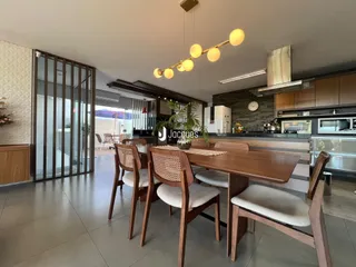 Uma sala de jantar com mesa de madeira e cozinha moderna em um imóvel no Brasil.