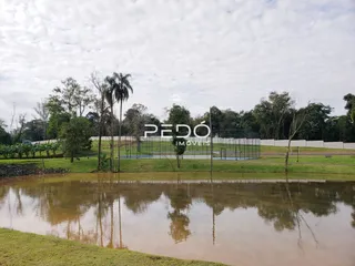Vista de um campo com água e vegetação ao fundo.