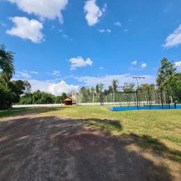 Vista externa de um terreno gramado com céu azul.