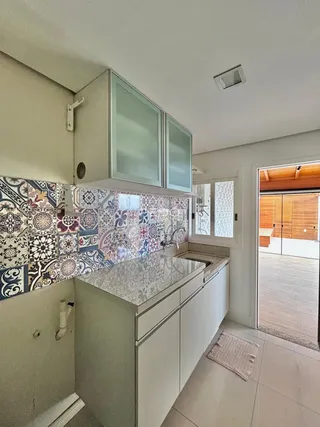 Foto de uma cozinha com revestimento cerâmico colorido e armários brancos.