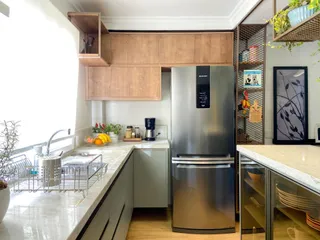 Cozinha moderna com bancadas claras e geladeira inoxidável.