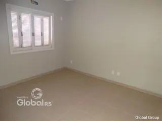 Ambiente interno de uma sala com piso de cerâmica e janelas com venezianas brancas.