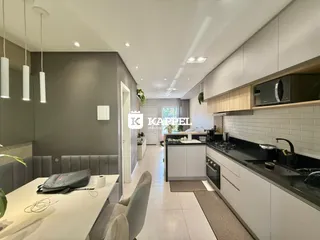 Vista interna de uma cozinha moderna com armários brancos e bancadas escuras.