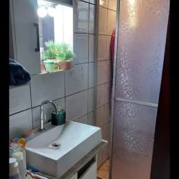 Vista de um banheiro com pia branca e azulejos claros.