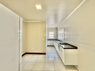 Corredor interno de uma residência com piso de cerâmica e armários brancos.