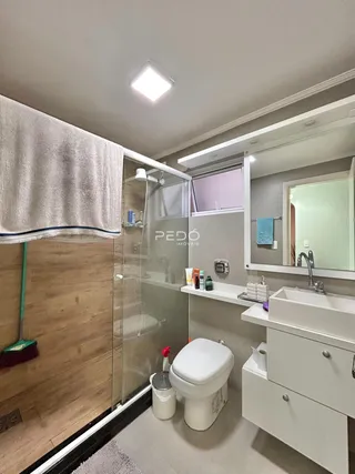 Banheiro com box de vidro e armário branco moderno.