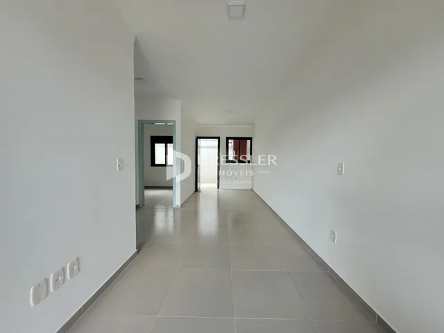 Corredor interno com piso de cerâmica claro e paredes brancas.