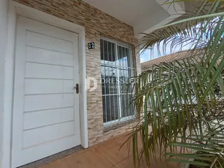 Fachada de uma residência em Lajeado, Brasil, com porta branca e revestimento de tijolo aparente.