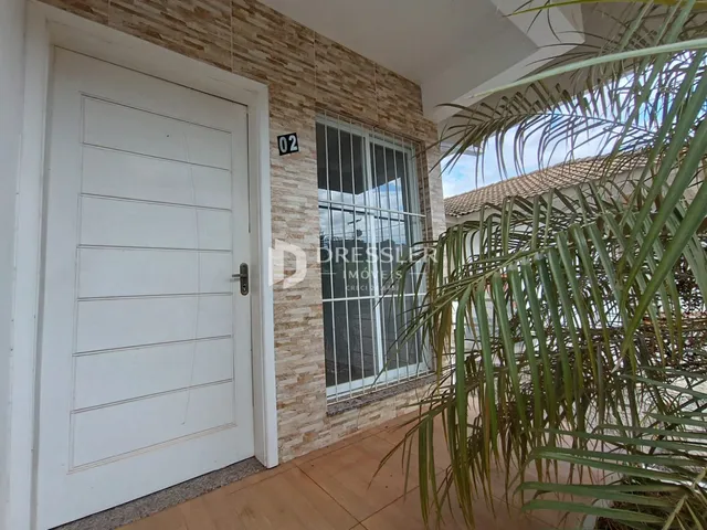 Fachada de uma residência em Lajeado, Brasil, com porta branca e revestimento de tijolo aparente.