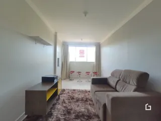 Sala de estar clara com sofá e piso de madeira.