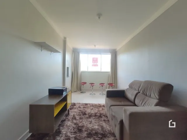 Sala de estar clara com sofá e piso de madeira.