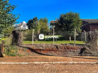 Vista externa de uma propriedade com cerca de arame e vegetação em um dia ensolarado.