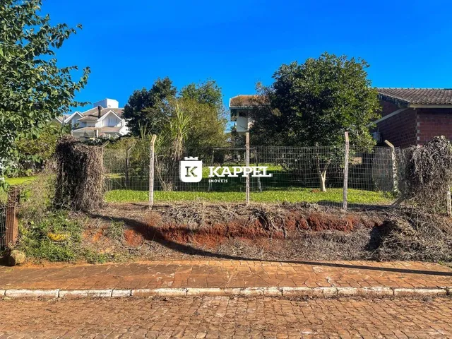 Vista externa de uma propriedade com cerca de arame e vegetação em um dia ensolarado.