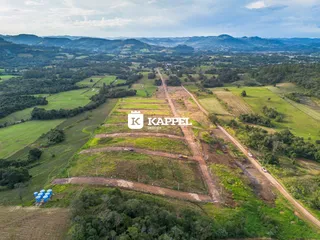 Vista aérea de uma paisagem rural com campos verdes e estradas de terra.