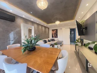 Sala de estar com mesa de madeira e sofá em um apartamento.
