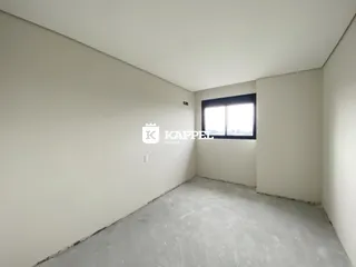 Ambiente interno vazio com paredes brancas e piso cru, mostrando um espaço sem acabamentos.