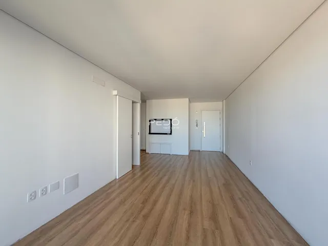 Hall de entrada com piso de madeira clara e paredes brancas.