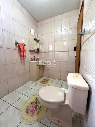 Foto de um banheiro com azulejos brancos e um vaso sanitário branco.