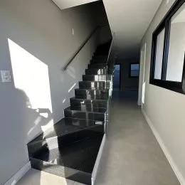 Hall de escadas com degraus escuros em um corredor interno.