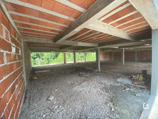 Foto de uma estrutura residencial em construção com paredes de tijolo aparente.
