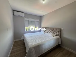 Quarto com cama grande e janela com persianas.