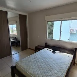 Quarto com cama grande e piso de madeira clara.