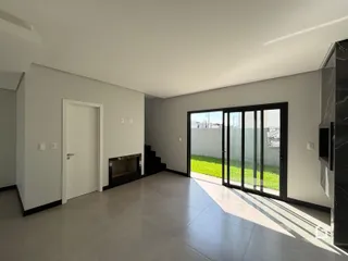 Ambiente interno moderno com piso claro e porta de vidro abrindo para o jardim.