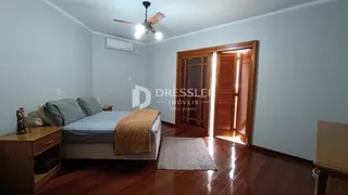 Quarto com cama e piso de madeira no interior da residência.