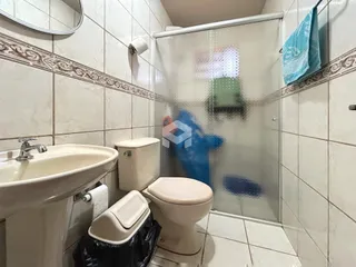 Foto interna de um banheiro com revestimento de azulejos brancos.