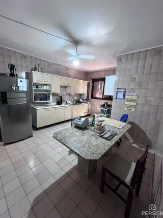 Foto da cozinha com armários brancos e piso de cerâmica.
