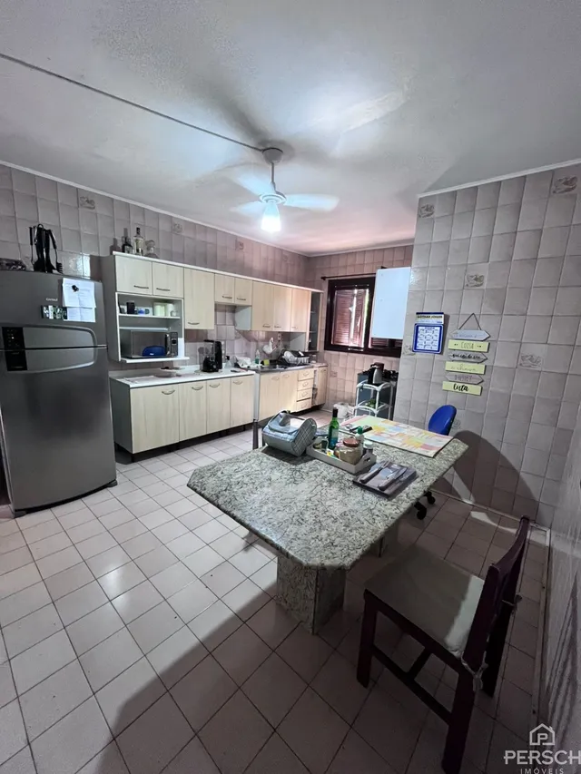 Foto da cozinha com armários brancos e piso de cerâmica.