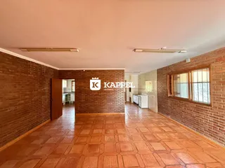 Hall de entrada com piso de terracota e paredes de tijolo aparente.