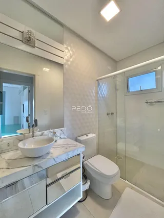 Banheiro moderno com bancada de mármore e box de vidro.