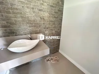 Foto de um banheiro com uma pia de apoio e parede texturizada.